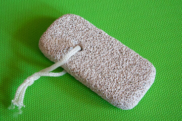 Skincare Tool Display. Pumice stone with string, presented on vibrant green, highlighting its...