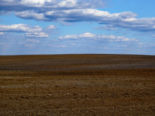 Obraz premium Horizon view of an open field with scattered clouds above.