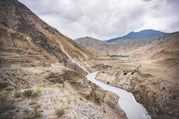 Road and river in a rocky gorge made of colored rocks in the Fan Mountains in Tajikistan