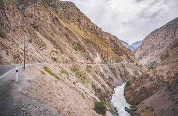 Road and river in a rocky gorge made of colored rocks in the Fan Mountains in Tajikistan