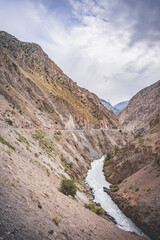 Road and river in a rocky gorge made of colored rocks in the Fan Mountains in Tajikistan