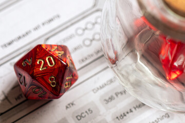 Red D20 Dice Beside Glass Jar on RPG Character Sheet
