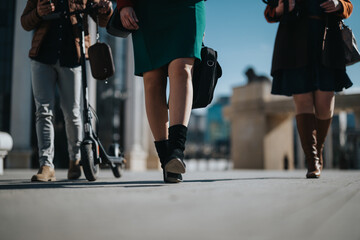 Obraz premium Focused low angle view of businesspeople's legs walking in a city, symbolizing teamwork and movement.