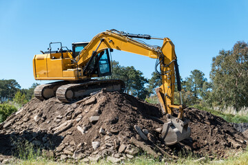 Obraz premium Retroescavadora em cima de um monte de cascalho a carrega-lo para o triturador