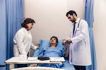 Obraz premium Doctor Visiting Patient On Ward. Hospitalized man lying in bed while doctor checking his. physician examining patient in hospital room. Hospital Ward