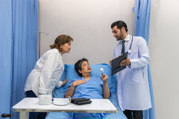 Obraz premium Doctor Visiting Patient On Ward. Hospitalized man lying in bed while doctor checking his. physician examining patient in hospital room. Hospital Ward