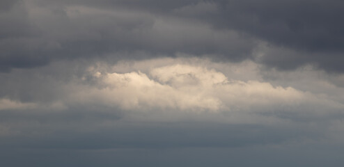 Dark, gloomy clouds gray and white with slight peek of light from sun