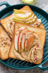 Toasts with peanut butter and pear slices on a green serving tray, vertical shot, middle close-up, selective focus