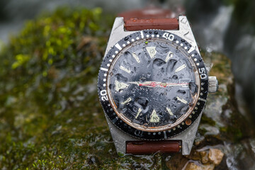 A robust watch from the 70s still withstands the elements in the wild creek, its glass speckled...