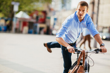 Smiling young businessman riding a bicycle in city