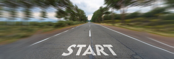 Asphalt road surrounded by mountains, "start" written on the road