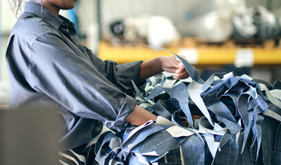 A hand holding shredded raw denim fabric in a denim factory. Industrial fabric and fashion manufacture. Stylish blue denim fabric for wholesale and jean recycling.