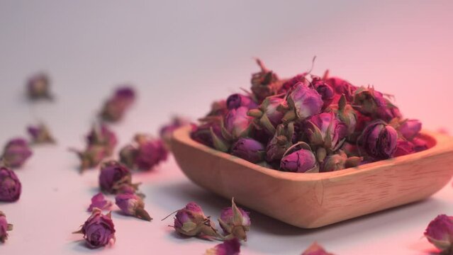 Wooden plate filled with dried damask roses with red ambient light