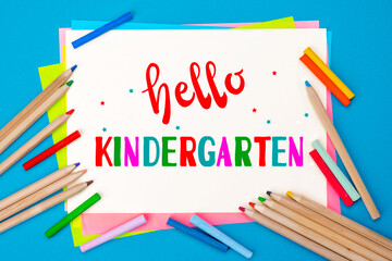 Hello kindergarten background. Top view flat lay concept. Childish lettering, colored paper, supplies, stationery for Pre-school, nursery school, kindergarten or preschool educational