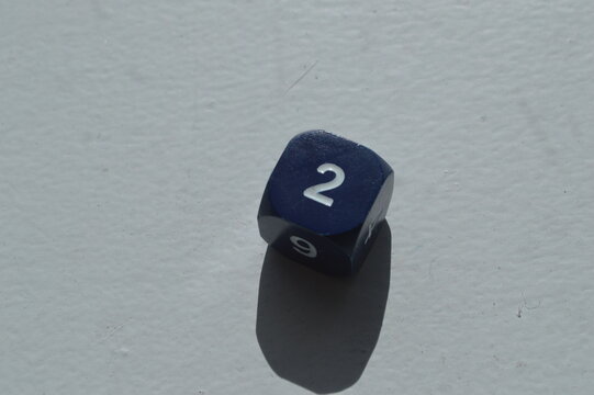 Blue D6 die showing 2 in sunlight on white background