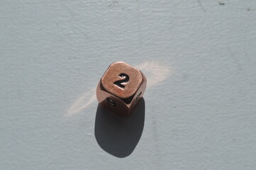 Copper D6 die showing 2 in sunlight on white background