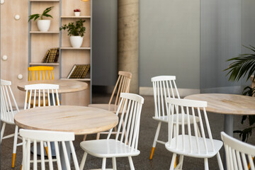 Modern restaurant interior background. An empty wooden table and chairs in a cafe. The cafe is filled with furniture such as white chairs and tables