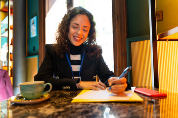 Business woman writing a document in a coffee shop smiling