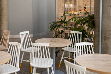 Modern restaurant interior background. An empty wooden table and chairs in a cafe. The cafe is filled with furniture such as white chairs and tables