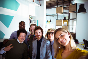 Group of diverse coworkers taking a selfie in a creative office space