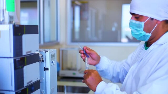 scientist inserting injection in a machine. science experiment syringe inserting filling inside an HPLC machine inside view in a Scientific experimental laboratory for research development analysis.	
