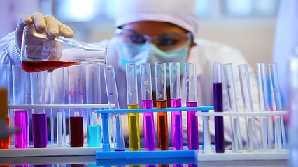scientist mixing chemicals in flask, beaker, test tube. chemist experimenting. science experiment in a beaker flask with colorful pink chemicals liquid in laboratory with medical lab equipment. 