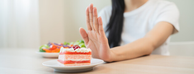Dieting young asian woman or girl use hand push out, deny sweet cake and  salad vegetables, eat...