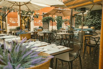 A charming outdoor dining area adorned with tables, chairs, and colorful umbrellas, inviting guests to enjoy a meal in a picturesque setting under the open sky