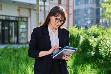 Portrait of business mature woman with digital tablet, outdoor