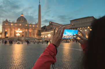 A person stands in awe, raising their cell phone to capture the magnificence of a towering...