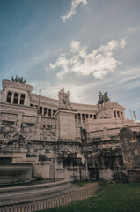 Naklejka premium A grand, imposing building stands tall in the background, with a large, ornate fountain in front of it. Water flows gracefully from the fountain, creating a peaceful and serene atmosphere