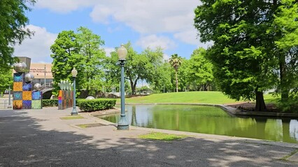 panning footage of a gorgeous spring landscape at Louis Armstrong Park with lush green trees and grass, a lake, blue sky and clouds in New Orleans Louisiana USA