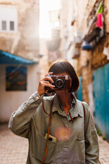 woman photographer with a camera takes pictures outdoors. Beautiful woman takes pictures outdoors using an analog camera. travel to Arab countries.