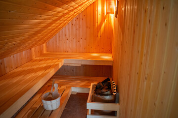 Gemütliche Sauna mit Saunaofen und Hölzernerm Saunakübel mit Holzkelle in warmen Licht.