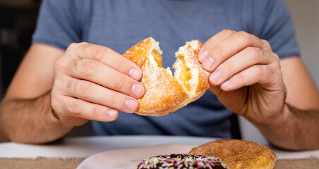 Man eating doughnut with apricot jelly. Czech Donut in hands closeup.