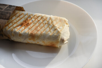 Meat shawarma on a white plate. A meat delicacy. Gyros kebab.