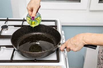 housewife pours frying oil into a frying pan.