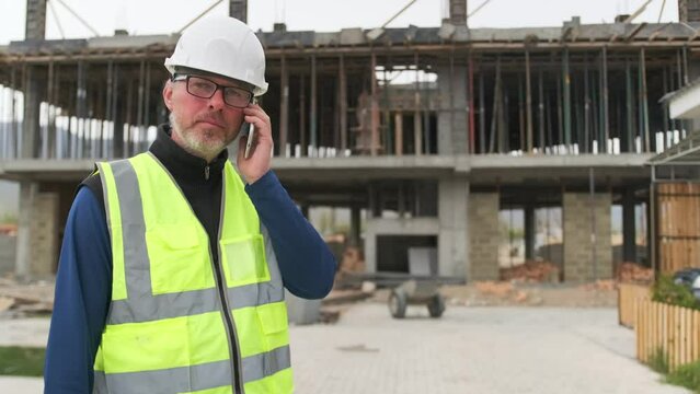 Civil engineer have nervous phone call, builder talking on mobile smartphone discussion on construction site, worker with dissatisfied face conducts difficult negotiations.