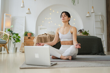 Yoga mindfulness meditation online. Woman practicing yoga with online lessons in laptop at home....