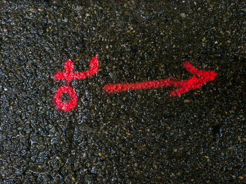 une fleche r&eacute;alis&eacute;e avec une bombe de peiture sur le goudron d'une route mouill&eacute;e