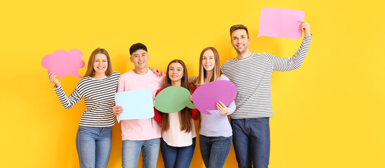 Group of young people with blank speech bubbles near color wall