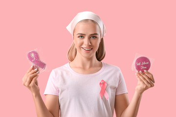 Young woman with ribbon and bagged cookies on pink background. Breast cancer awareness concept
