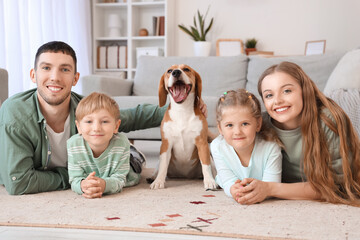 Little children with their parents and Beagle dog lying on floor at home