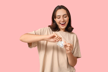 Young woman with condoms on pink background. Safe sex concept