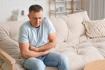 Mature man suffering from bellyache at home
