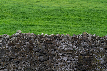 A fence made of stones. Against a background of grass.