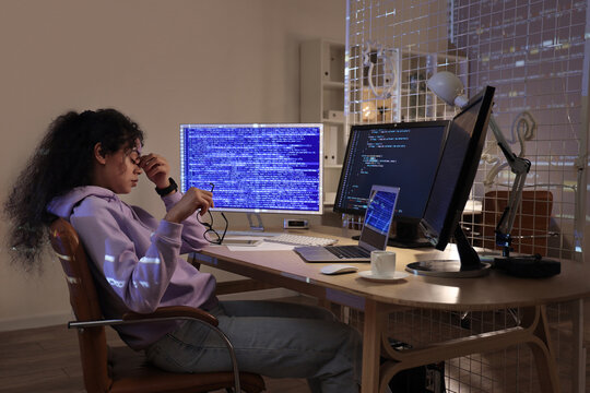 Tired female African-American programmer with eyeglasses sitting in office at night
