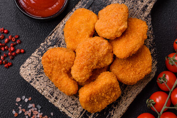 Delicious fresh crispy chicken nuggets on a dark concrete background
