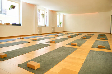 A yoga studio with a lot of mats and blocks. No people.