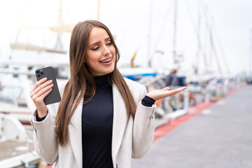 Young pretty woman using mobile phone at outdoors with surprise facial expression